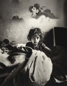Roman Vishniac, [Sara, sitting in bed in a basement dwelling, with stenciled flowers above her head, Warsaw], cs. 1935–37. © Mara Vishniac Kohn, courtesy International Center of Photography. Roman Vishniac Rediscovered. 
